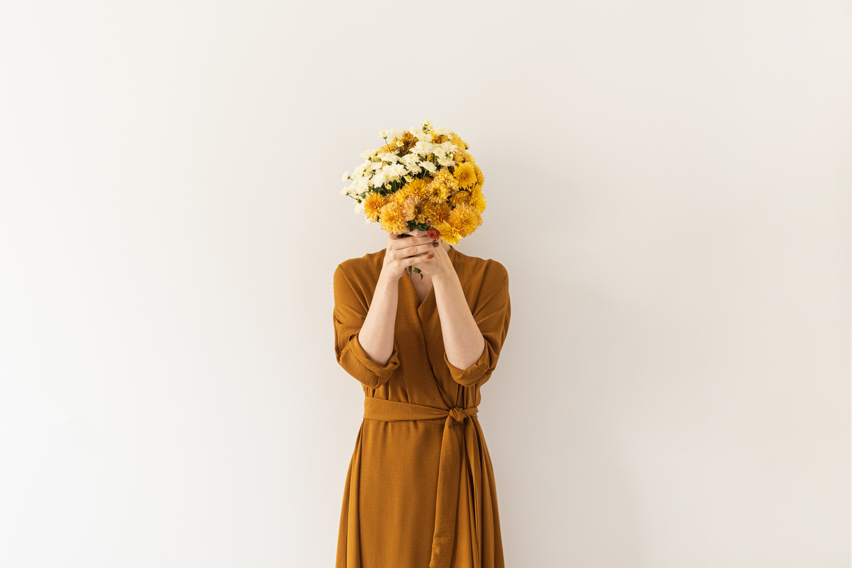 Woman Covering Face with Bouquet of Flowers 